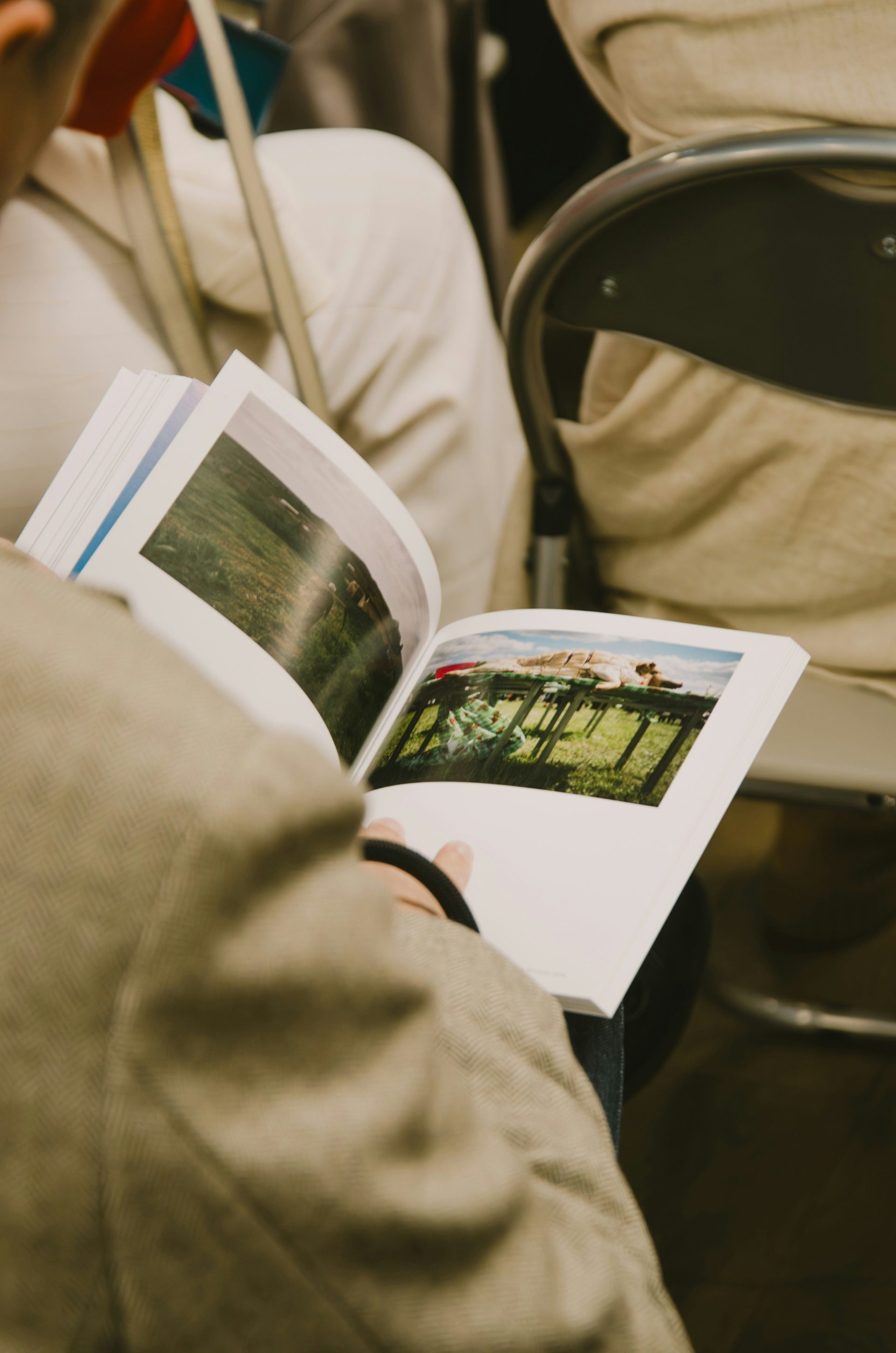 A person in a beige blazer holding an open book with landscape photographs